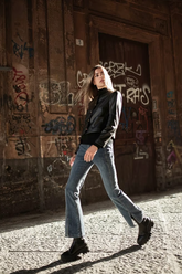 a lady wears a black leather jacket with flared jeans